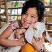 Photo of smiling  child with her new lamb, thanks to Heifer